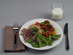 Обеденная тарелка со сбалансированными порциями мяса, овощей и крахмала со стаканом молока.