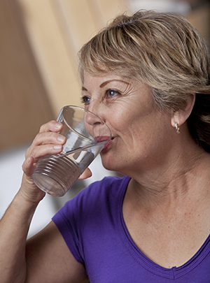 Femme buvant un verre d'eau.