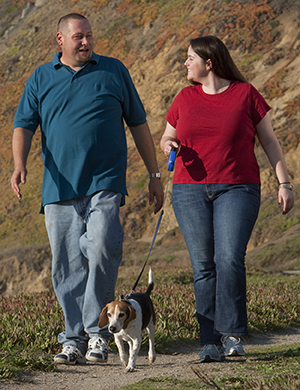 Un homme et une femme promenant un chien.