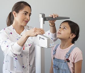 Un professionnel de la santé mesurant la taille d'une fille.