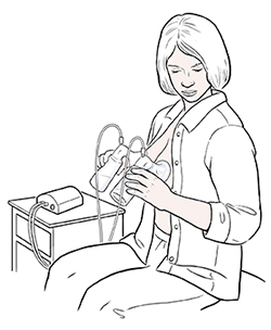 坐在椅子上的女子用电动双乳泵从两个乳房中挤奶。