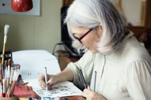 女性は紙やペンを使ってアートを制作し、忙しくしている。
